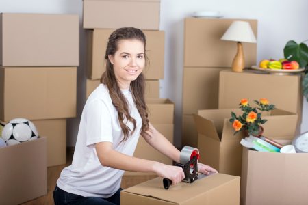 Woman happily unpacking moving boxes in living room