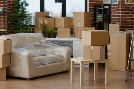 No people in empty living room apartment with carton boxes on stack, moving cardboard storage packaging in new household. Nobody in relocation property with interior furniture cargo.